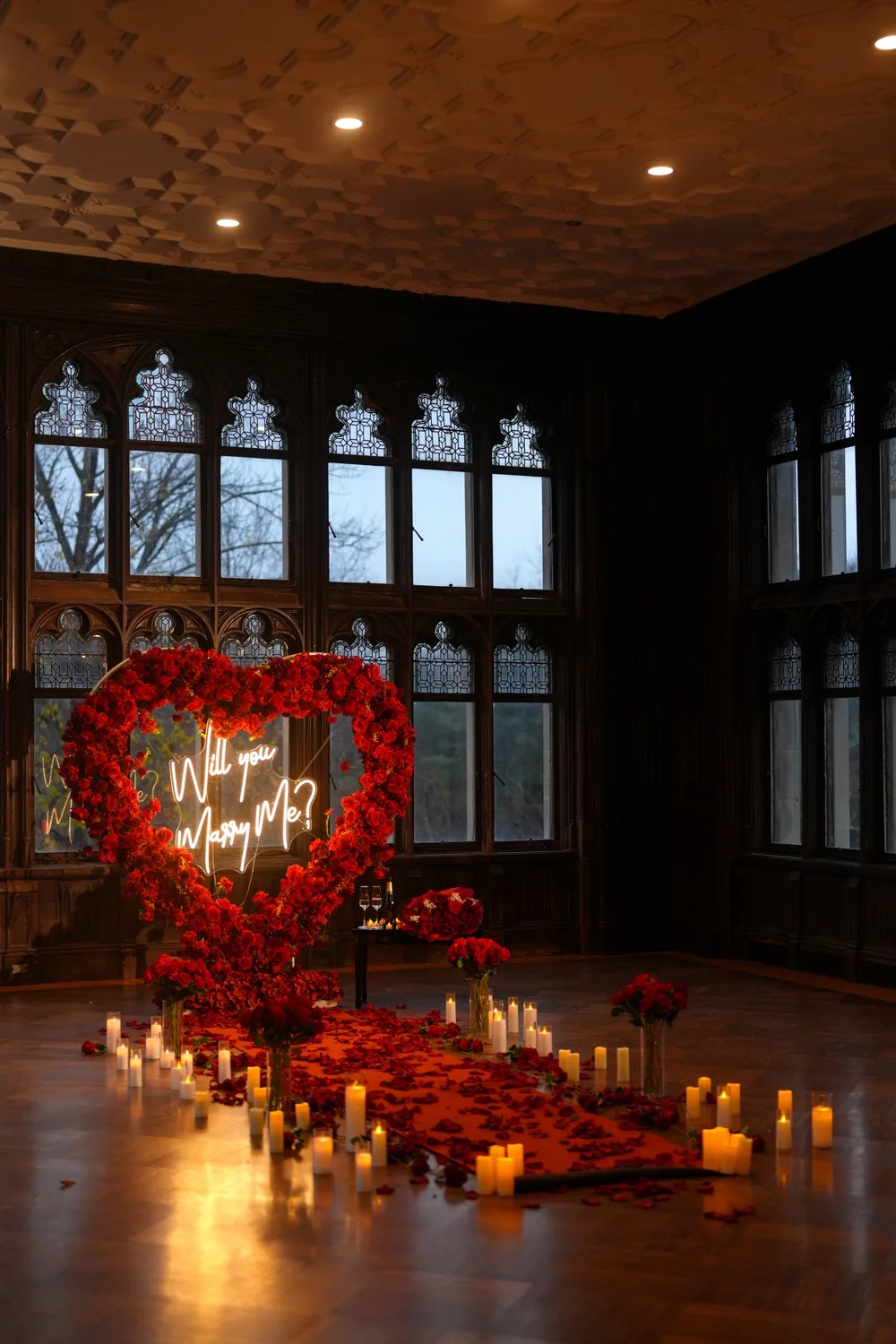 A red rose heart and candles in a dark wood-panelled hall