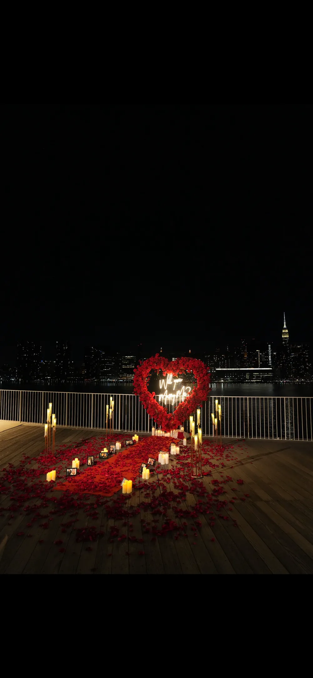 A small red heart lit on a dark rooftop at night