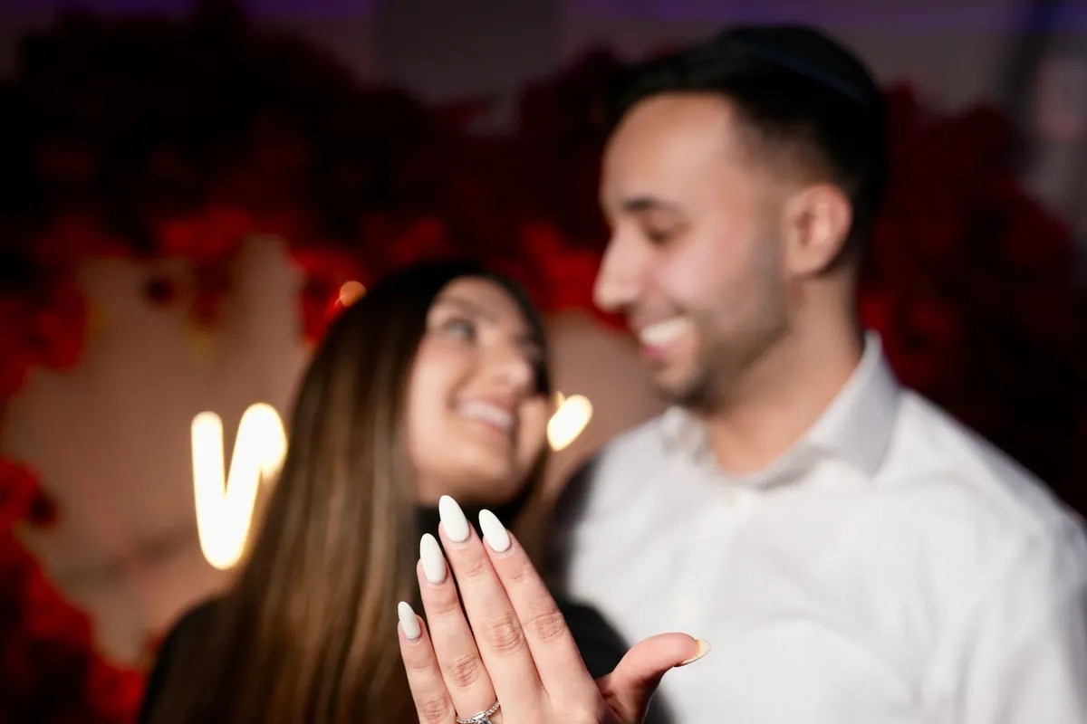 She smiles at him and shows her engagement ring