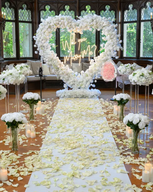 A white rose heart and petal aisle lined with white flowers in a wood-panelled hall with leaded windows