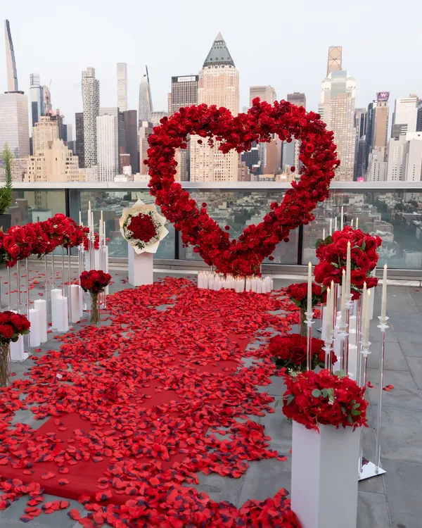 A red rose heart and petal aisle on a glass-railed terrace facing the Manhattan skyline