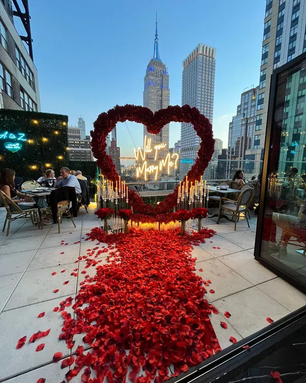 A red rose heart and candlelit aisle on a restaurant terrace below the Empire State Building